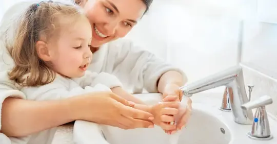 Kid washing hands with her mom